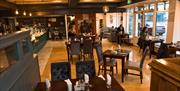 Interior of Helena's Coffee Shop and Bistro featuring a warm, inviting atmosphere with wooden floors, cosy seating arrangements, and soft lighting. Ta