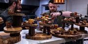 An image of two men plating up food onto tiered wooden stands