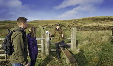 A couple at a gate with a tour guide in the Sperrin Mountains