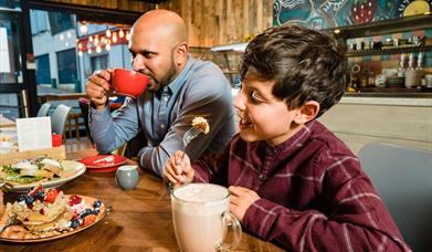 A father and son drinking hot chocolate in a restaurant