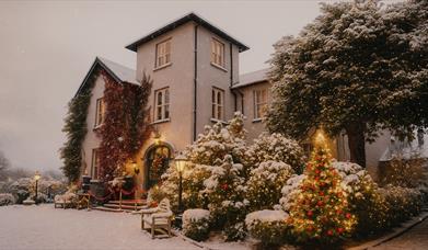 Corick House shown in the snow with festive lighting on the trees