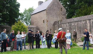 Group of people listening to a man in costume in front of Benburb castle