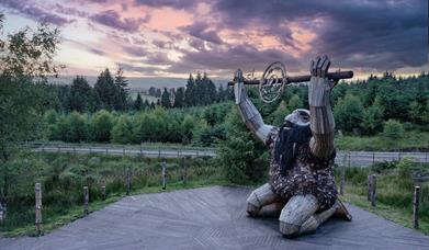 Ceoldán, the Stargazer, kneeling on a timber boardwalk