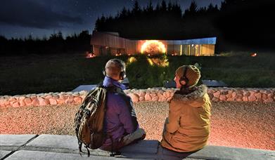 A couple with headphones watching the outdoor projection of the sun