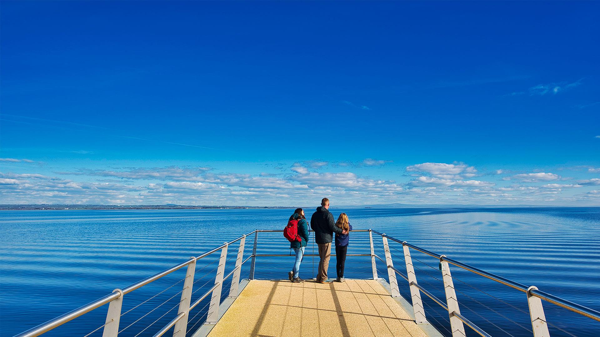 A family standing on the viewing platform overlooking Lough Neagh.