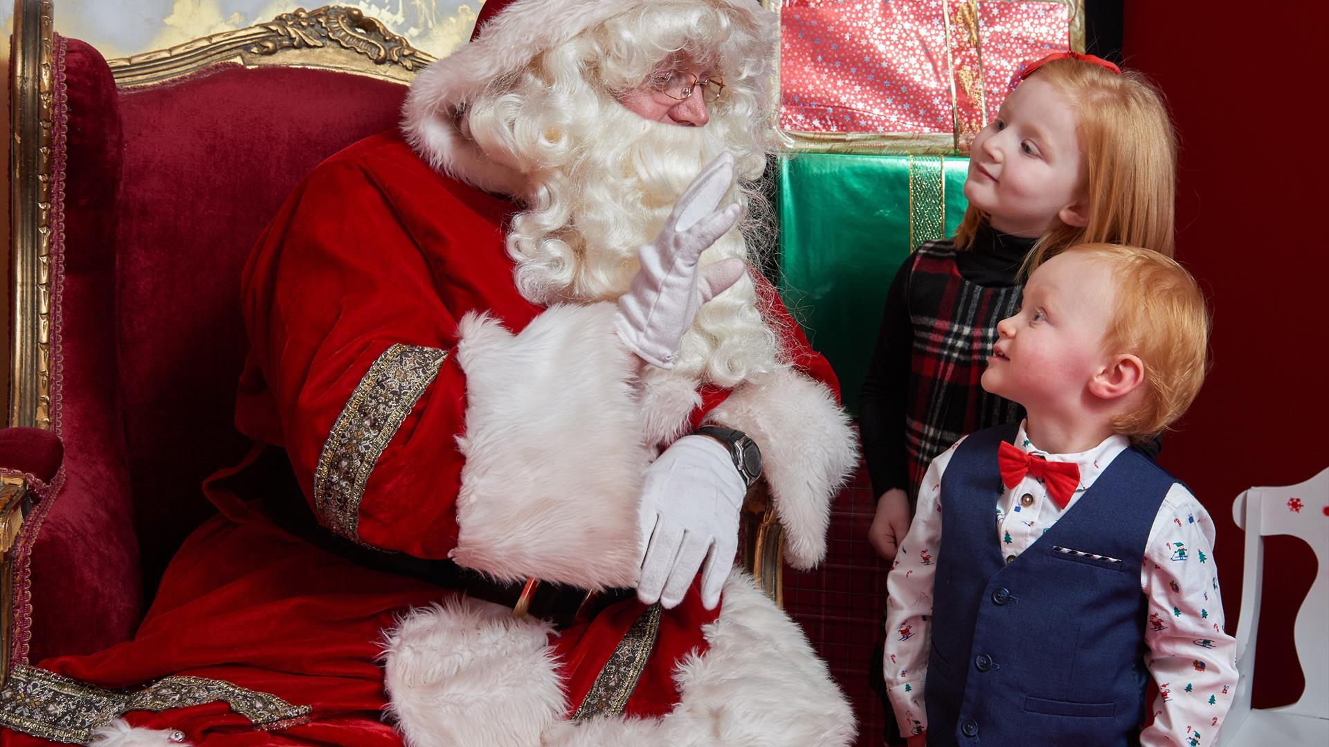 Two children talking to Santa in his grotto