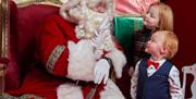 Two children talking to Santa in his grotto
