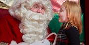 Young girl excitedly telling Santa what she would like for Christmas