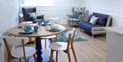 Open plan dining and living area with sofa, 2 armchairs and table and 3 chairs