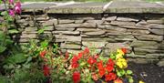 A colourful flower bed and stone wall