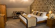 double bed with 2 bedside lockers and lamps.  2 seater sofa, wardrobe and chest of drawers in bedroom