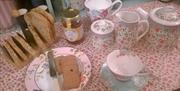Table set with bread, jams, teapot, cups and milk jug.