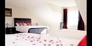 Family room with rose petals scattered on double bed.  Includes 2 double beds and 1 single bed