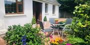 Back garden with table and chairs, greenery and colourful flowers