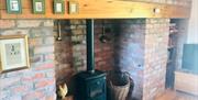 Image of the wood burner with the brick surround and wooden mantle piece