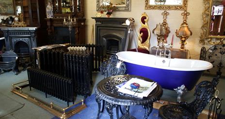 picture showing an old bathtub, radiator, table and chairs and other antiques