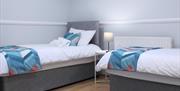 Twin bedroom with white linen on 2 single beds and orange and blue colour scheme