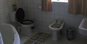Tiled bathroom with bath, toilet and sink