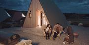 couple toasting marshmallows at firepit in front of glamping pod