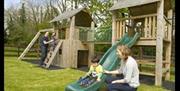 family playing on wooden play frame with slide and ladder