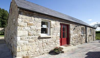 entrance to cottage with red door and stone walls 