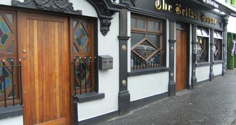 A white building with ornate black features and a wooden door