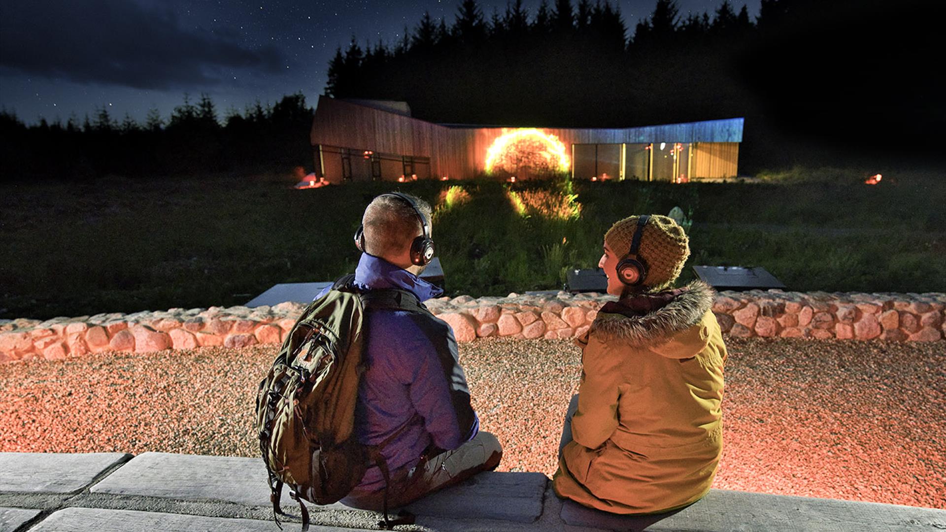 A couple with headphones watching the outdoor projection of the sun
