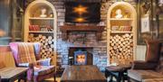 lounge area with wood burning stove in brick fireplace with armchairs and tables