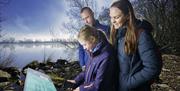 A family looking at the interpretative panels on the shores of Lough Neagh.