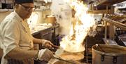 A chef cooking with flames in the pan