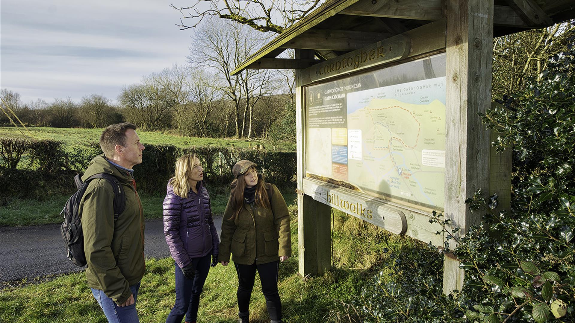 A group looking at signage at the start of Carntogher Heritage Trail