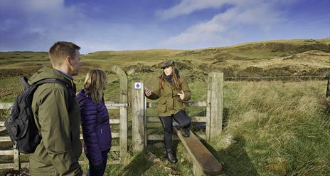 A couple at a gate with a tour guide in the Sperrin Mountains