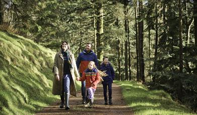 A family walking through Davagh Forrest in Autumn