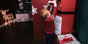 A child putting his letter to Santa in a red post box