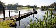 A man standing fishing on the jetty at Dungannon park lake
