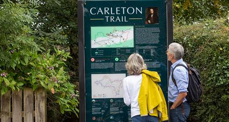A mature couple looking at a sign on the Carleton trail in the Clogher valley.