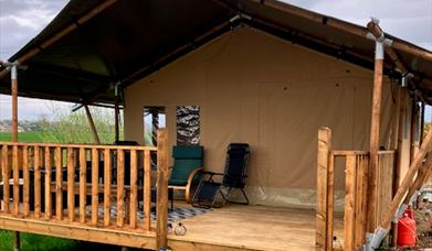 The outside of the tent with a covered deck and chairs