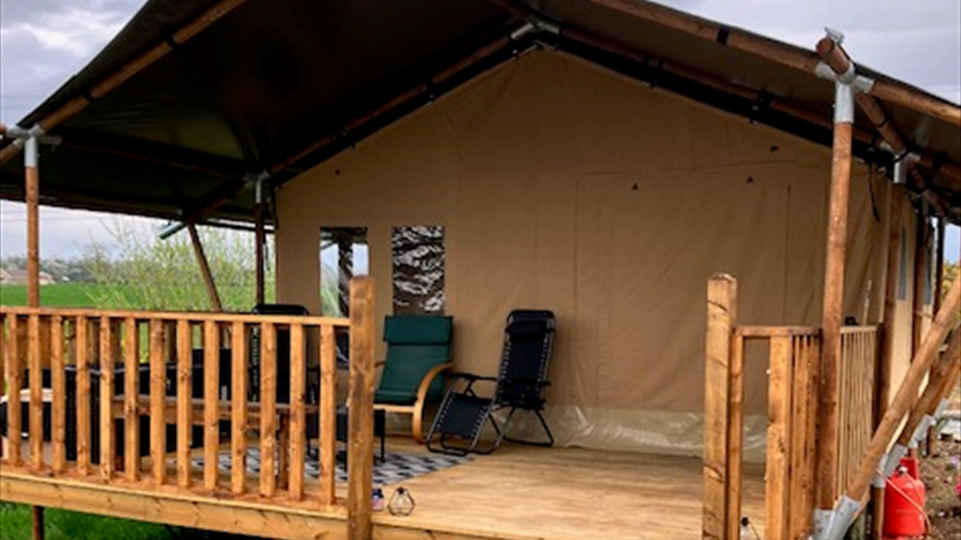 The outside of the tent with a covered deck and chairs