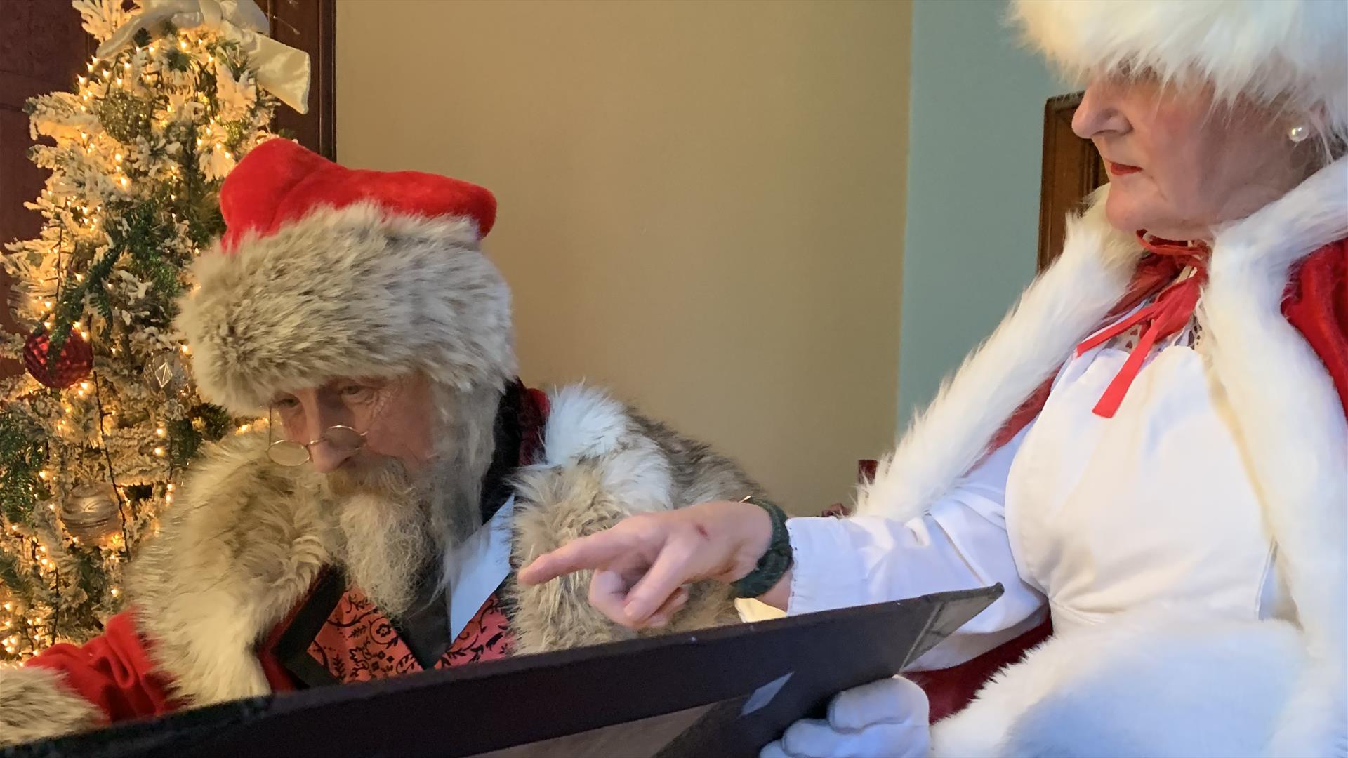 Santa and Mrs Claus reading the naughty and nice lists in Santa's study.