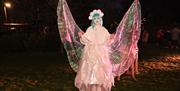 A woman dressed as a Christmas fairy is holding out her wings