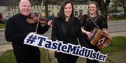 Musicians on the street of Moy Village with a Taste Mid Ulster sign
