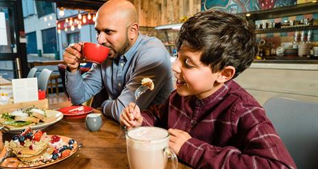 A father and son drinking hot chocolate in a restaurant