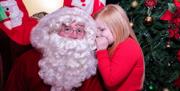 Young girl whispering in Santa's ear
