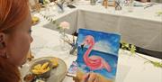 Girl painting sand on painting of flamingo