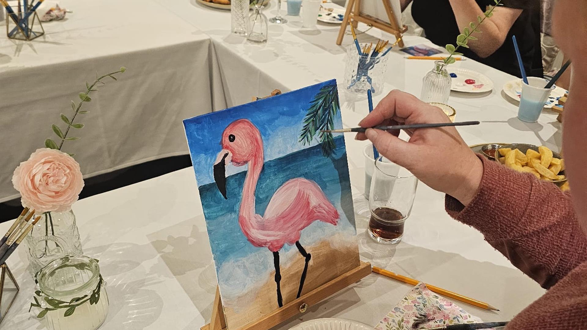 H shaped table with people painting a pink flamingo H shaped table with people painting a pink flamingo
