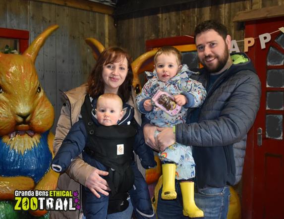 Image of two adults and two kids in front of a plastic bunny rabbit
