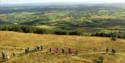 Drone image of walkers on Slieve Gallion with panoramic scenery stretching for miles and Lough Neagh in the far distance