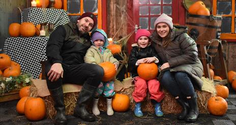 A family sitting on hay bales with Pumpkins
