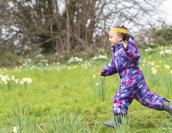 Girl running through field  wearing easter ears