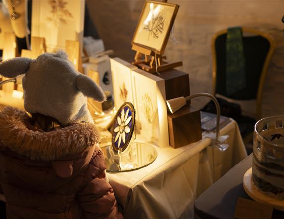 Girl admiring glasswork crafts at Castle Ward's Christmas Market